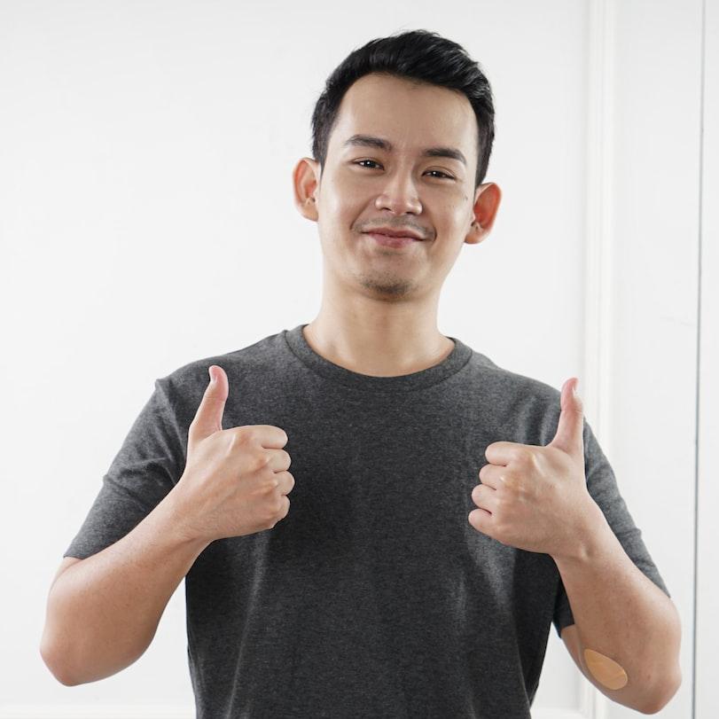 man in black tank top standing near white wall